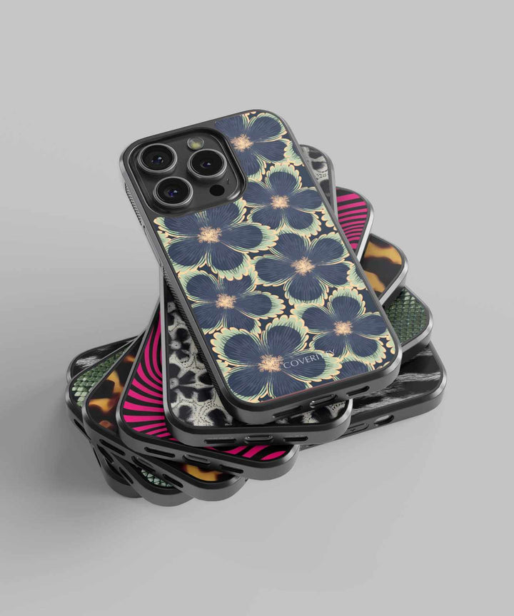 Stack of phone cases with floral and geometric designs on a gray background
